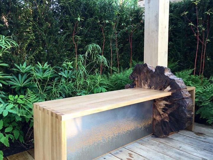 Sculptural garden bench combining timber, a metal panel and a natural burr end